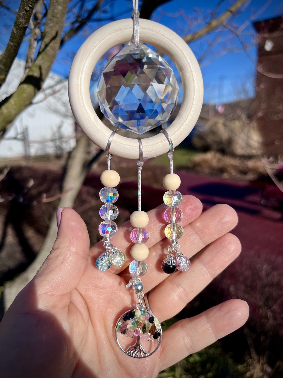 Crystal inside a wooden ring with 3 rows of beads hanging down.