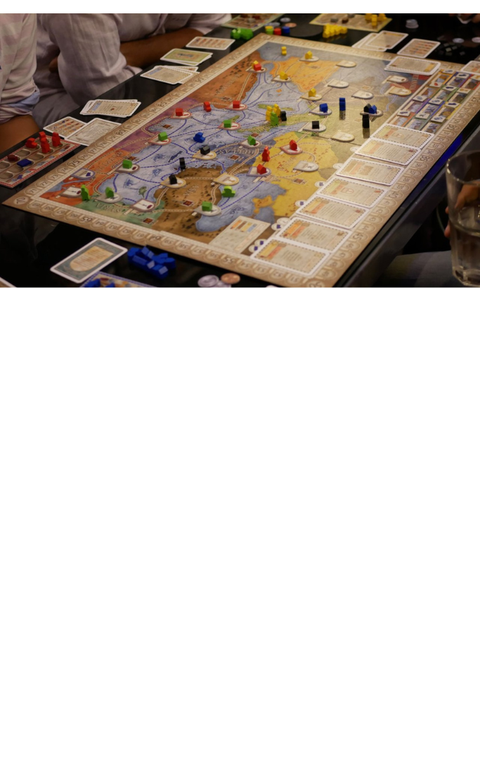 Game board with multiple pieces on the board with players around the board