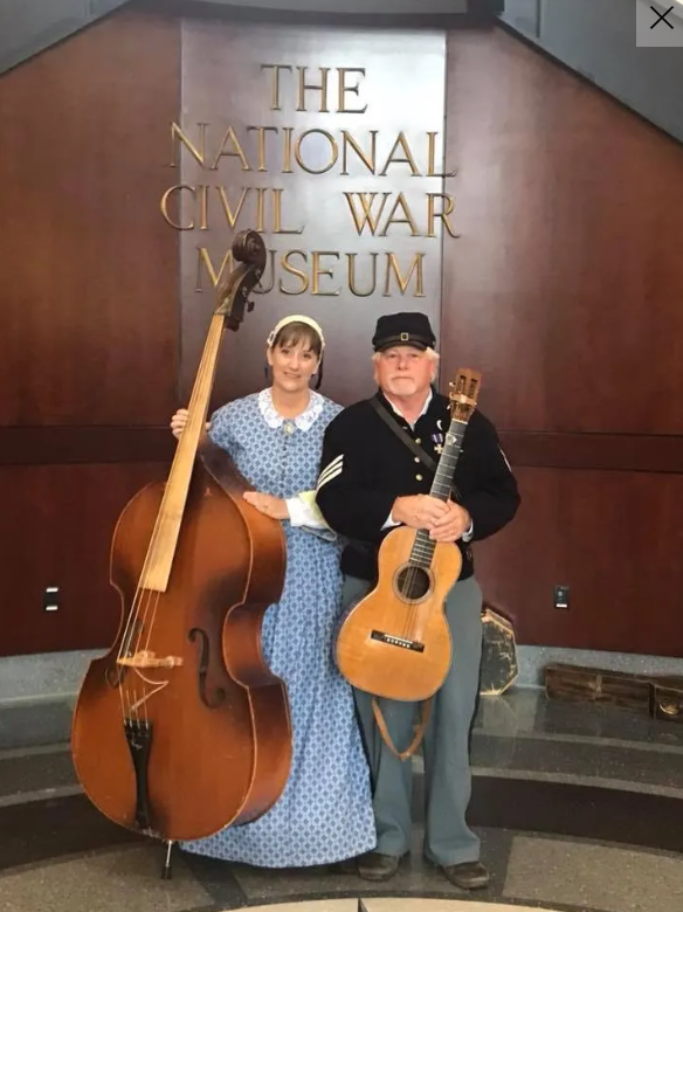 Man and woman dressed in Civil War costume each holding a musical instrument